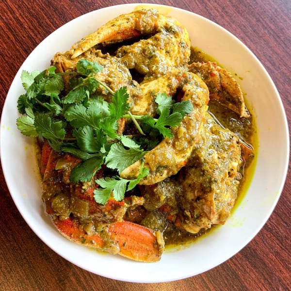 Pam's Caribbean Kitchen's curry crab, garnished with fresh cilantro, served in a white bowl.