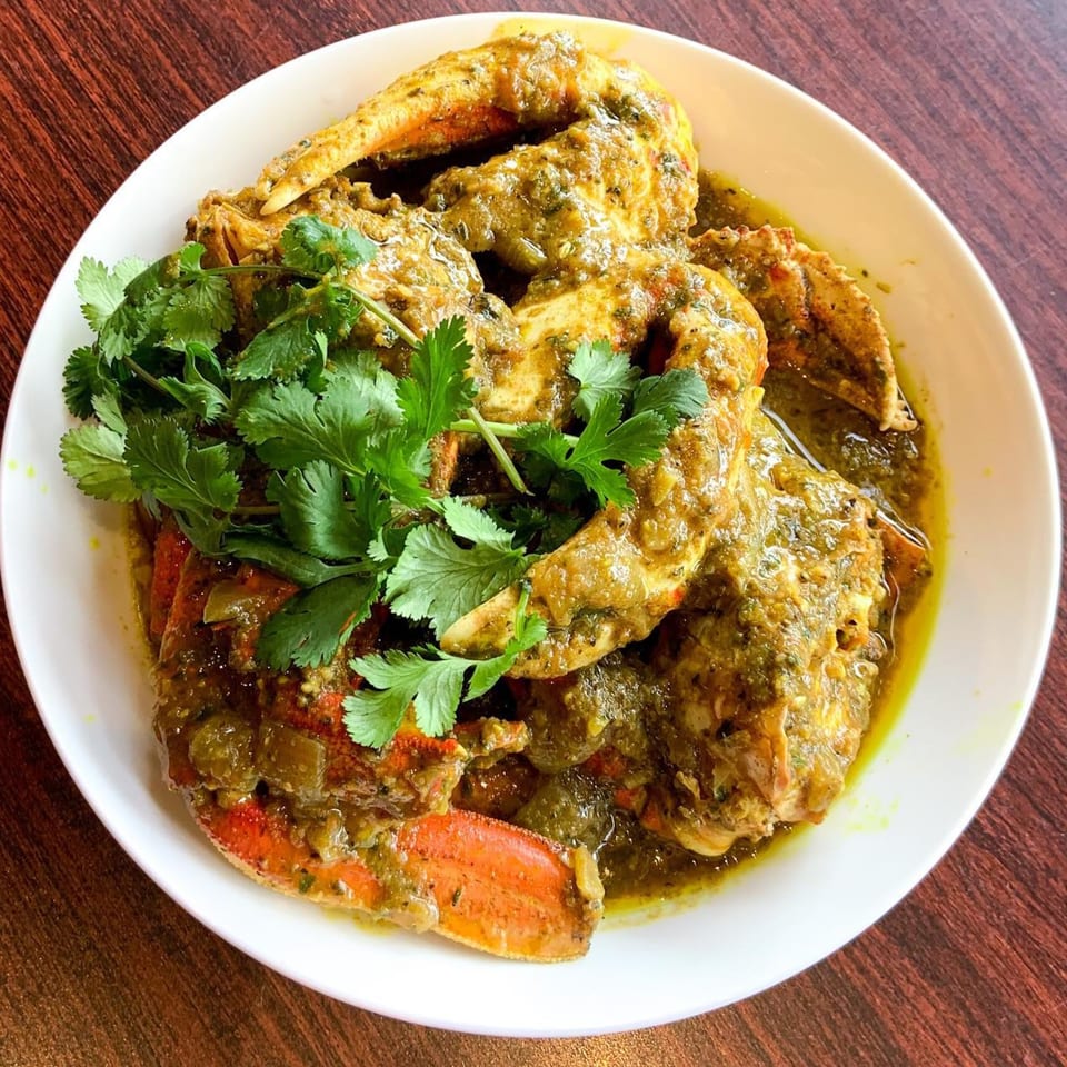 Pam's Caribbean Kitchen's curry crab, garnished with fresh cilantro, served in a white bowl.