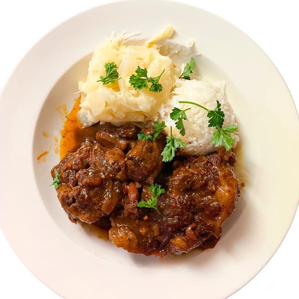 Pam's Caribbean Kitchen's brown stew chicken with white rice and steamed cabbage, garnished with parsley.