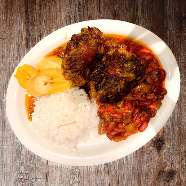 Pam's Caribbean Kitchen oxtail stew with rice, red beans, and plantains on a white plate.